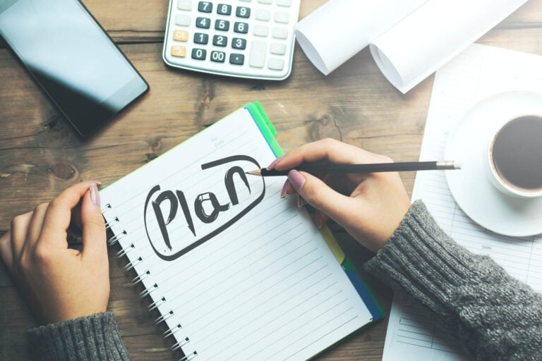 woman writing "Plan" in notebook